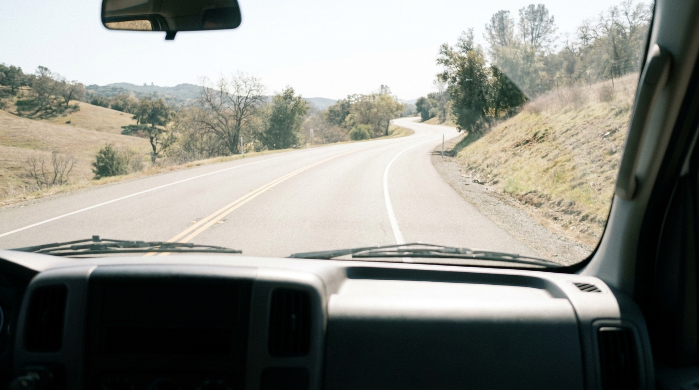 A view from inside a moving truck cab looking out at the open road ahead